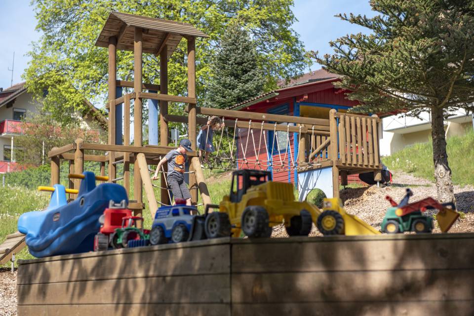 Kinder spielen auf einem Abenteuerspielplatz mit Holzstrukturen, Outdoor-Abenteuer im Familotel Mein Krug