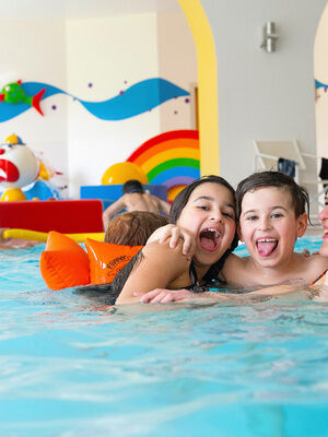 Familienhotel Mein Krug im Fichtelgebirge: Familie liegt sich lachend in den Armen im Indoor-Schwimmbad